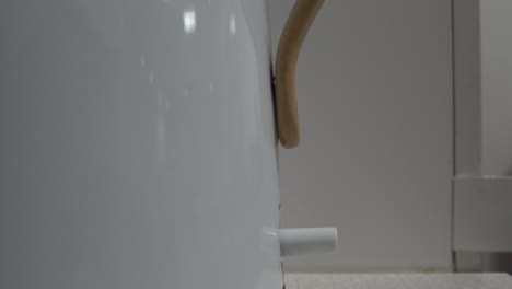 closeup shot of a white kettle boiling showing the switch clicking off at boiling point