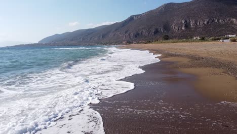 Salpicaduras-De-Olas-En-La-Playa-De-Arena-En-Monemvasia,-Peloponeso,-Grecia---Antena