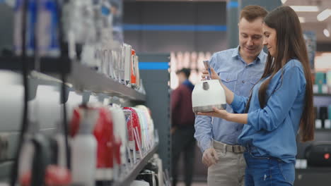 young family chooses electric kettle for their new home in appliances store