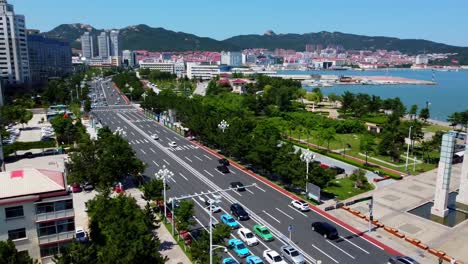 Aerial-panorama-shot-at-xingfu-park-overlooking-the-beautiful-xingfu-gate-on-the-coast-of-weihai-city,-chona-and-several-buildings-built-in-asian-architecture-with-a-busy-street-with-traffic