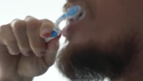 Close-up-profile-view-shot-of-a-bearded-man-brushing-teeth-against-white-background