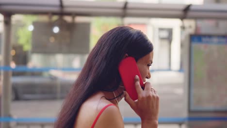a woman talking and smiling on a red phone outdoors