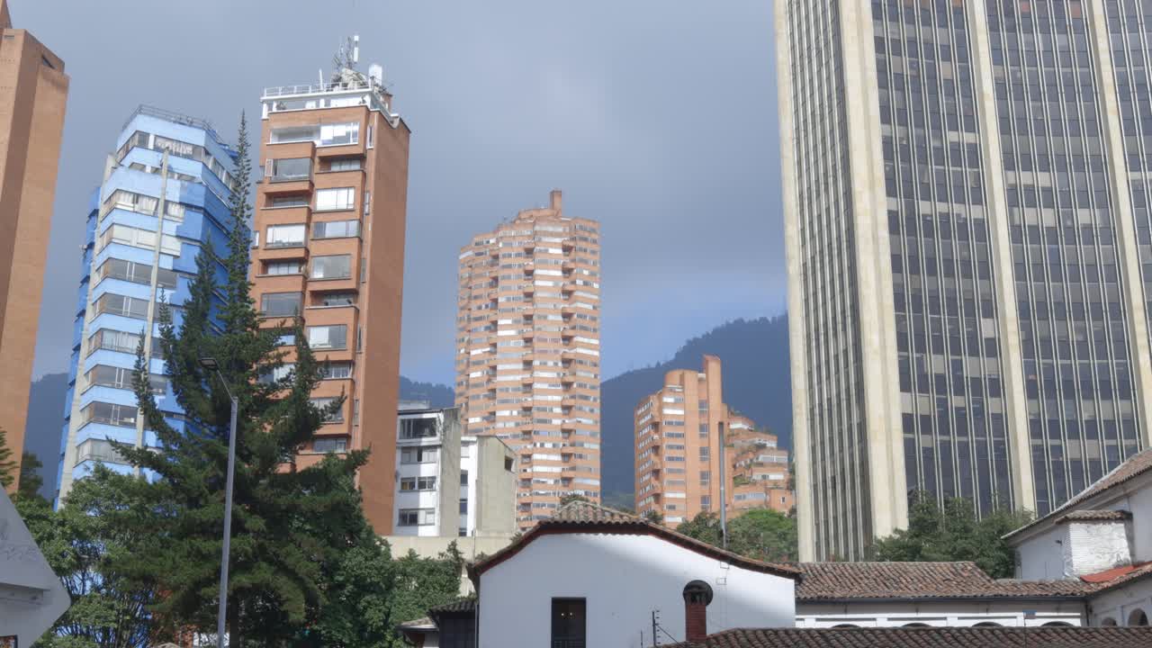 Establishing tilt up of Bogotá’s modern skyscrapers against cloudy mountains, Colombia capital city