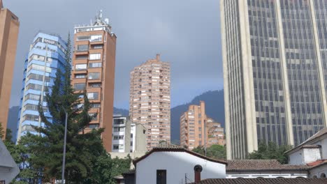 establishing tilt up of bogotá’s modern skyscrapers against cloudy mountains, colombia capital city