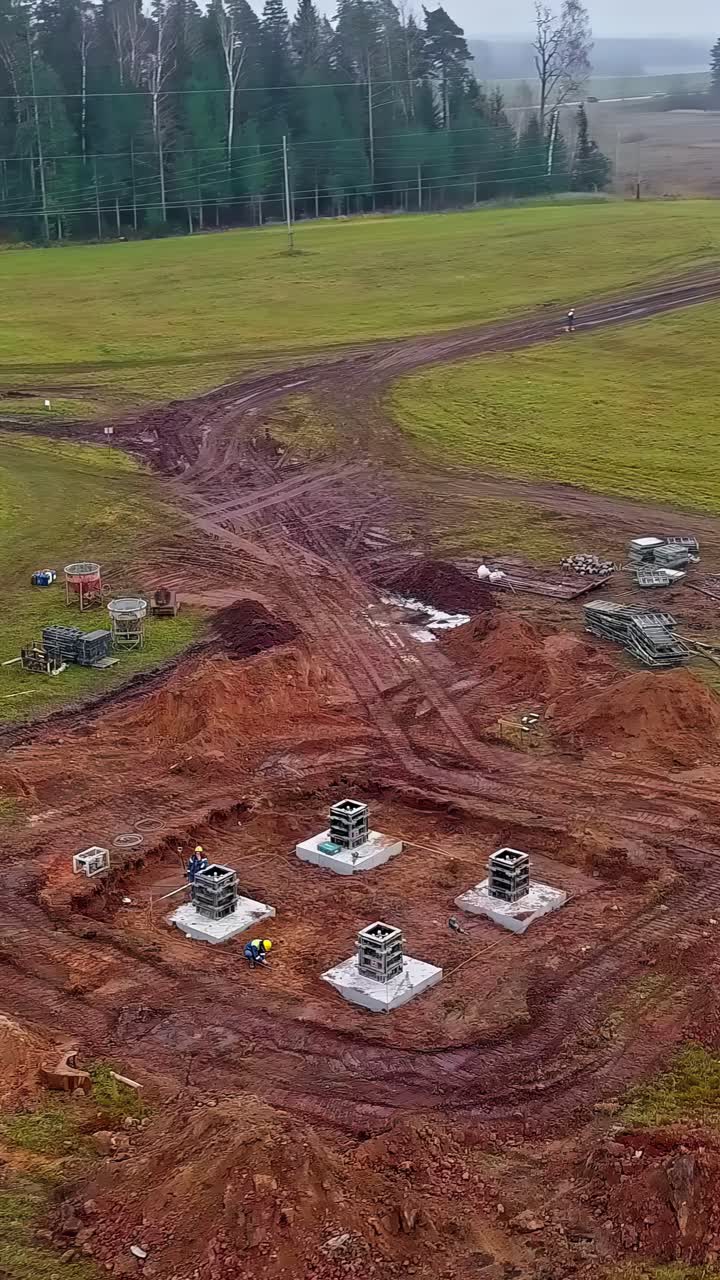 Vertical View Of Workers On The Construction Site Of A Wind Turbine. Aerial Drone Shot