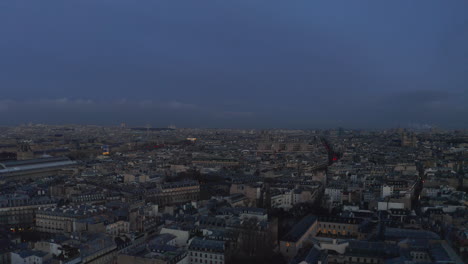 Forwards-fly-above-buildings-in-urban-borough.-Town-development-in-large-city-after-sunset.-Paris,-France