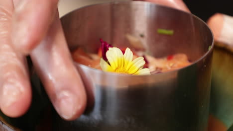 food plating - chef lifts the stainless moulder before serving the tuna ceviche with a beautiful daisy flower as garnish