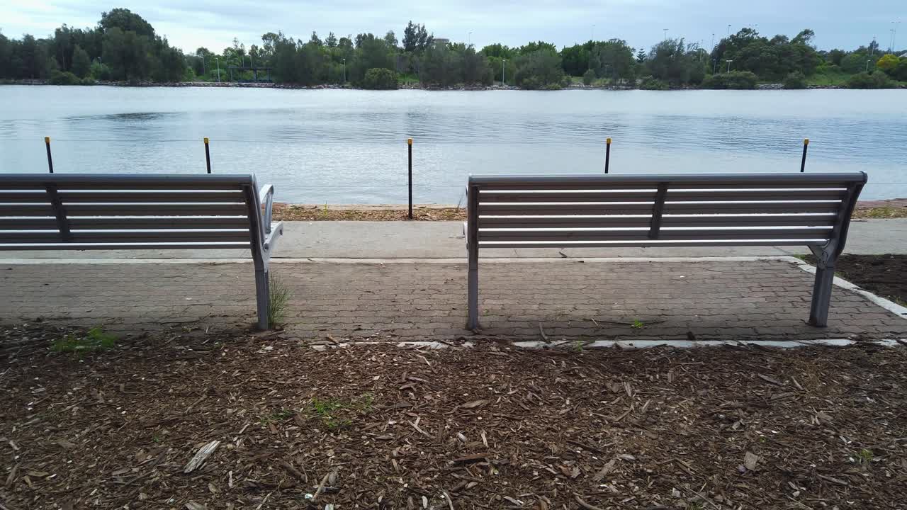 흐린 아침에 공공 공원에서 강가에 있는 두 개의 벤치