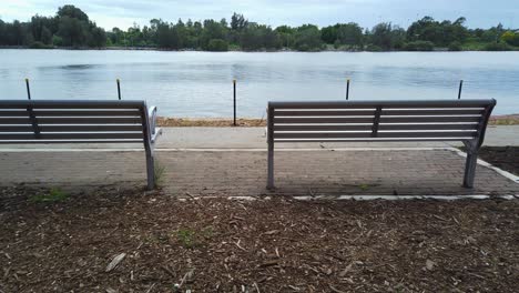 two benches by the river walk in the public park in a cloudy morning