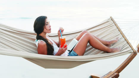 woman relaxing on hammock and using digital tablet