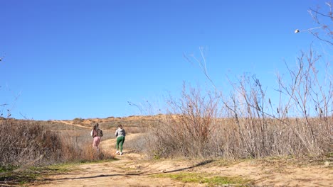 dos mujeres corriendo a través de un terreno accidentado en el campo