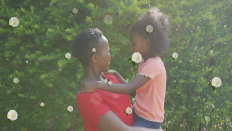 animation of roses over happy african american mother and daughter hugging in garden