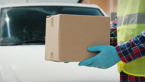 The-Courier-Hands-The-Parcel-Of-The-Recipient-Near-The-White-Delivery-Service-Van