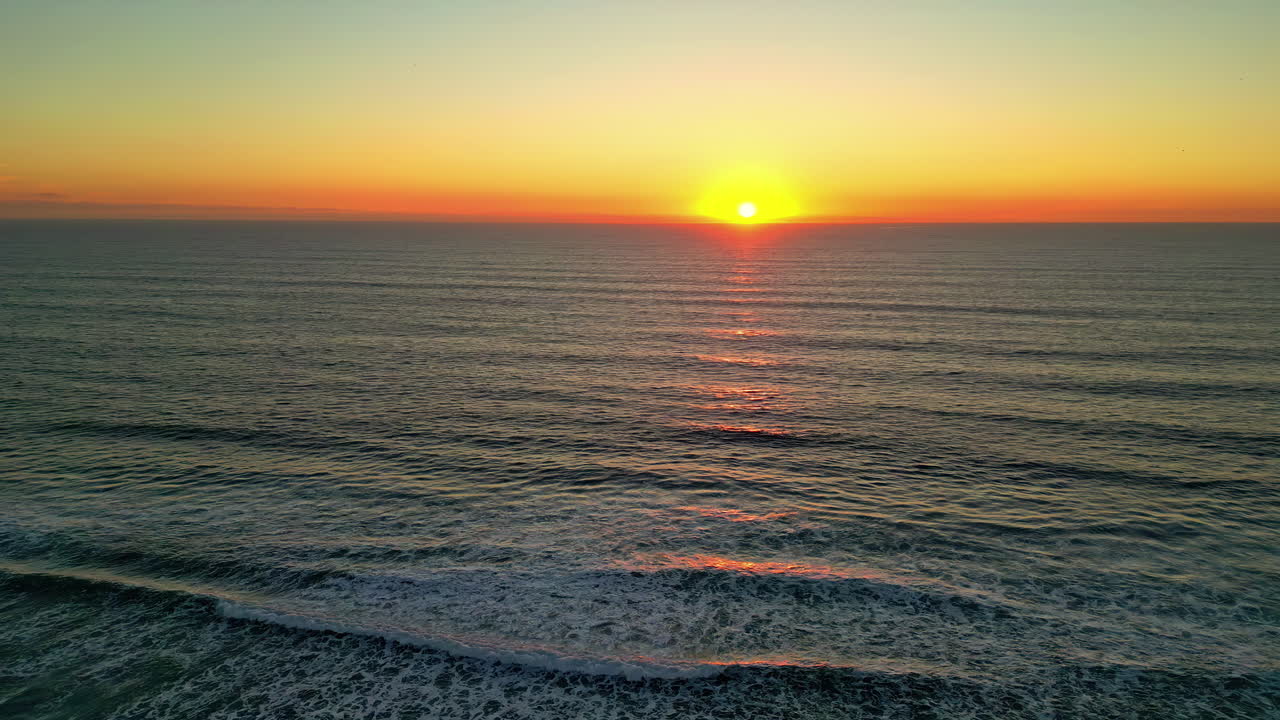 해변을 가로지르는 바다 파도와 함께 지평선에서 아름다운 노란색 반이는 일몰