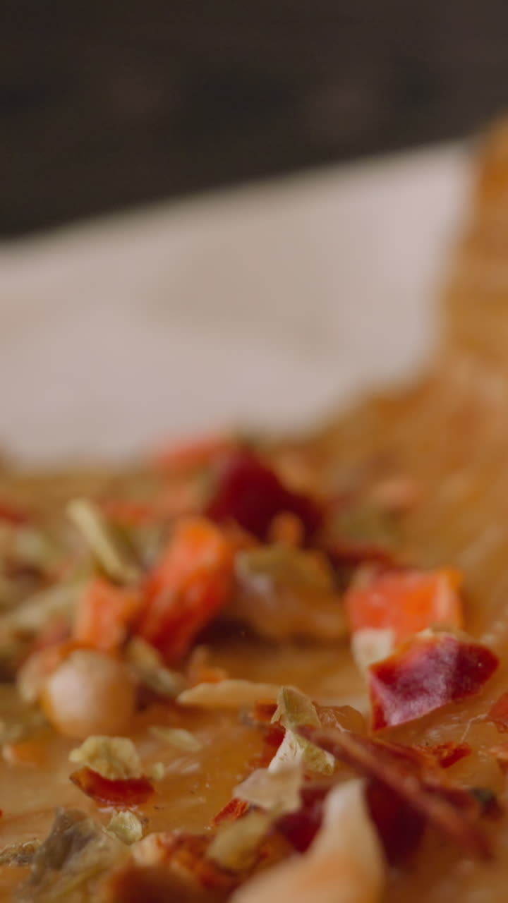 Spicy seasonings fall down onto delicatessen smoked trout piece with baked vegetables lying on parchment extreme close view slow motion