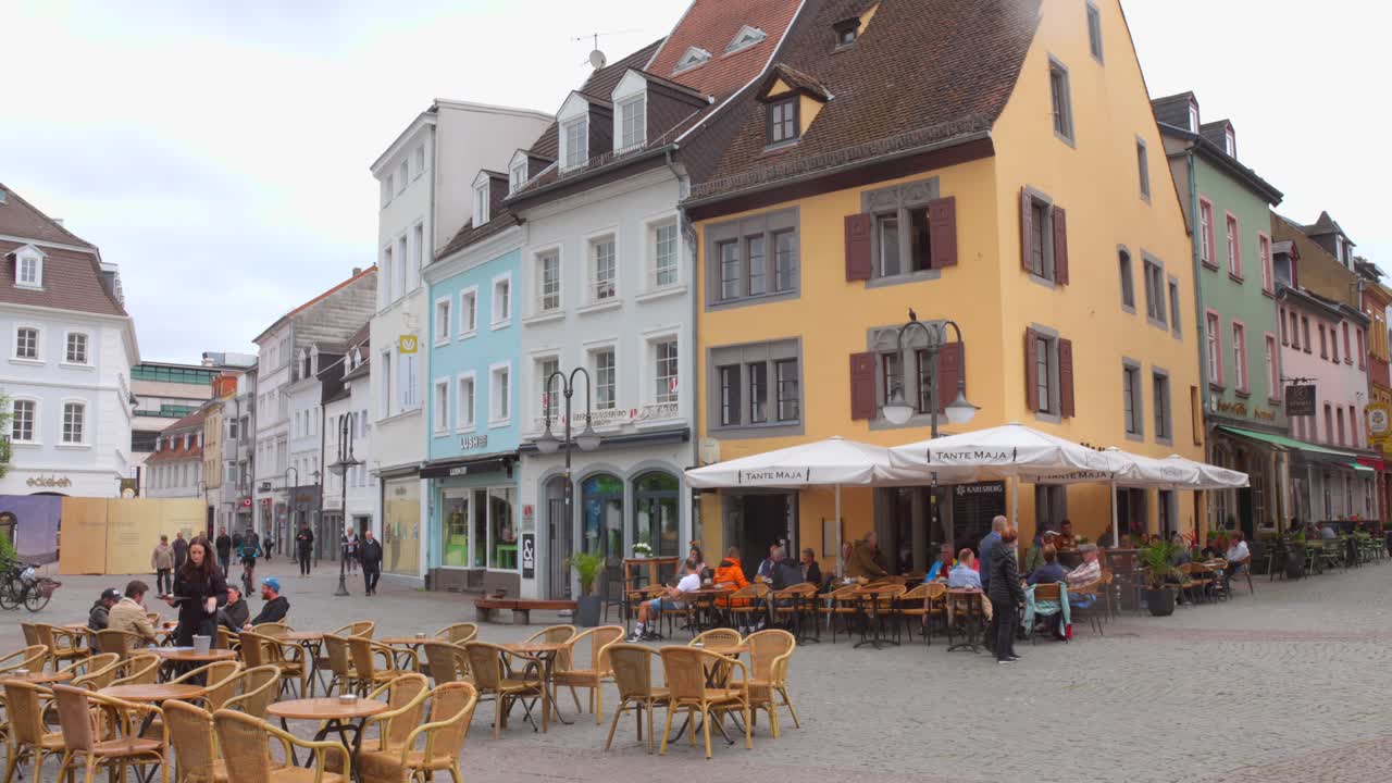 Colorful European buildings and outdoor cafes create a lively scene in a charming town square