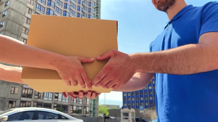 Delivery Person Handing Over a Cardboard Package to a Customer