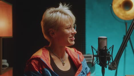 joyous woman talking in mic as recording podcast interview in studio