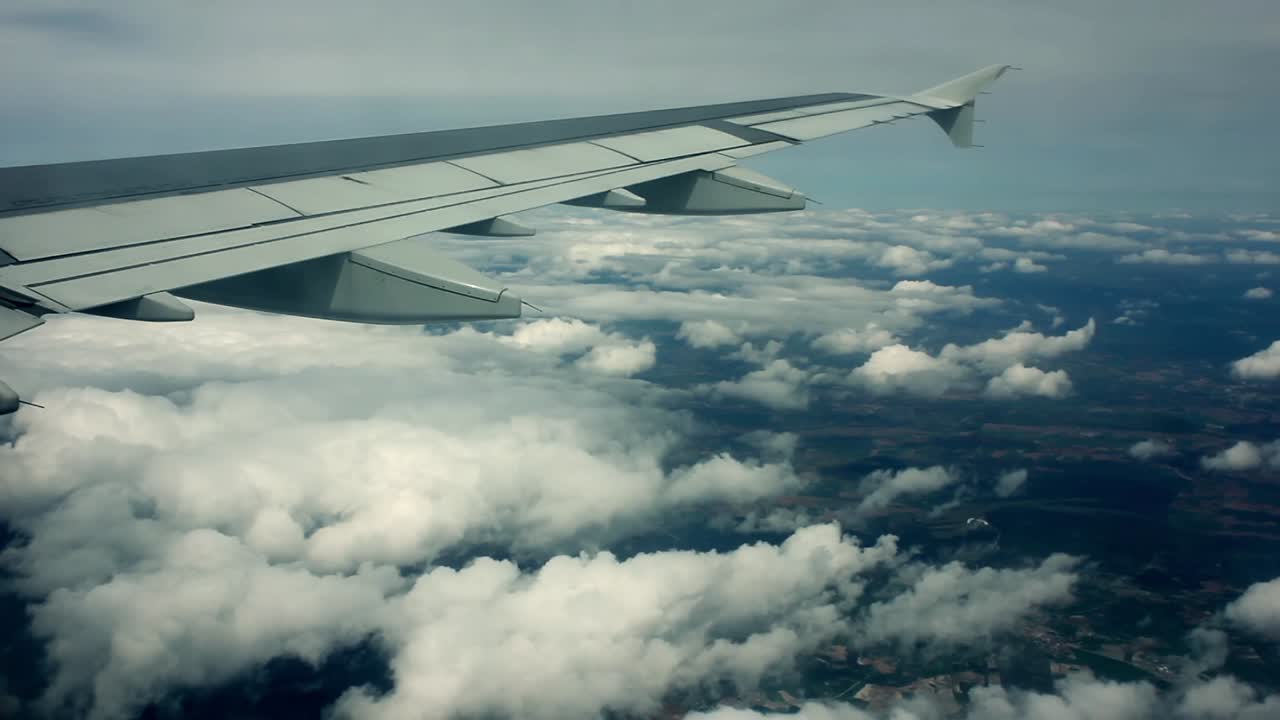 Udsigt fra flyvinge, der flyver over skyer og landskab