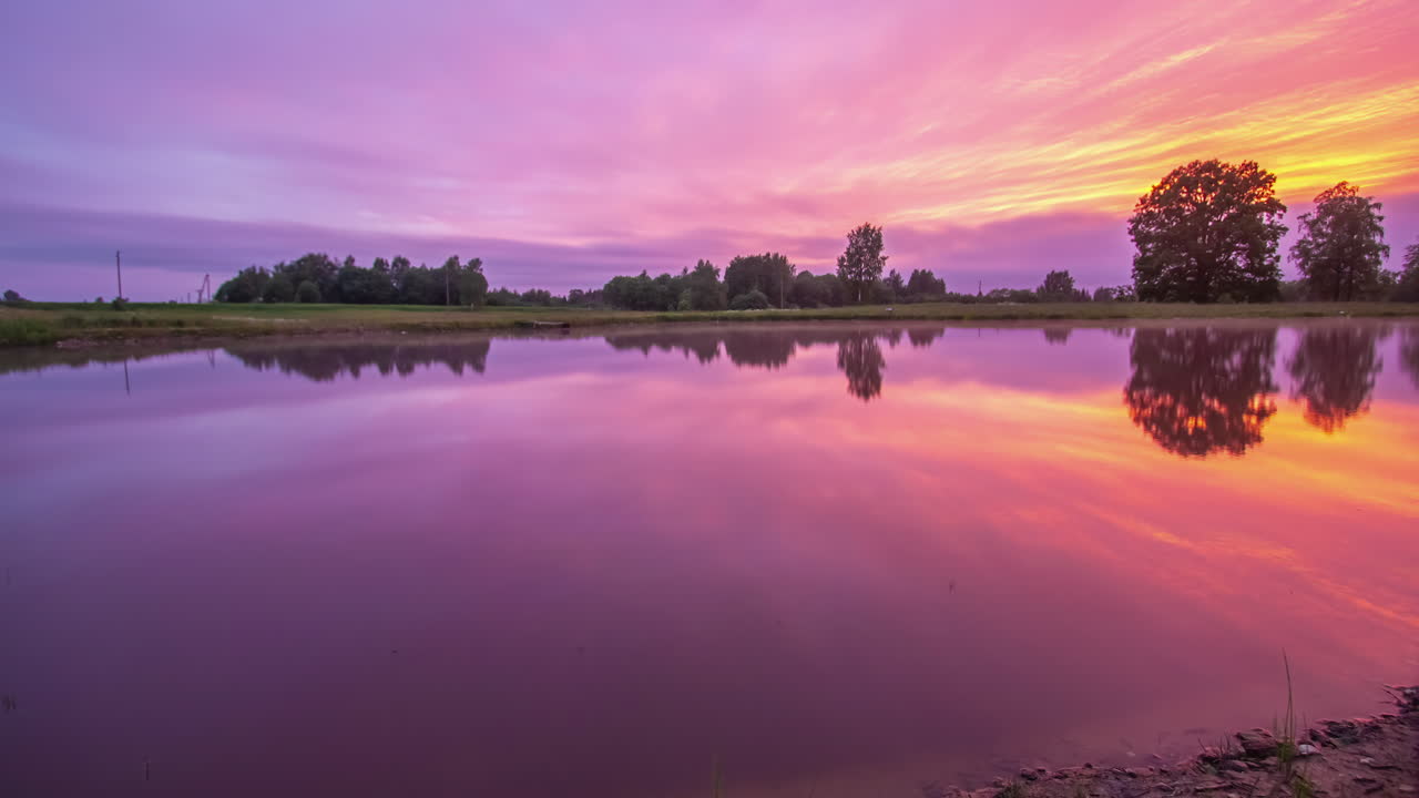 disparo en ángulo bajo al lado del lago bajo el colorido cielo de la puesta de sol con movimiento de nubes blancas en el lapso de tiempo