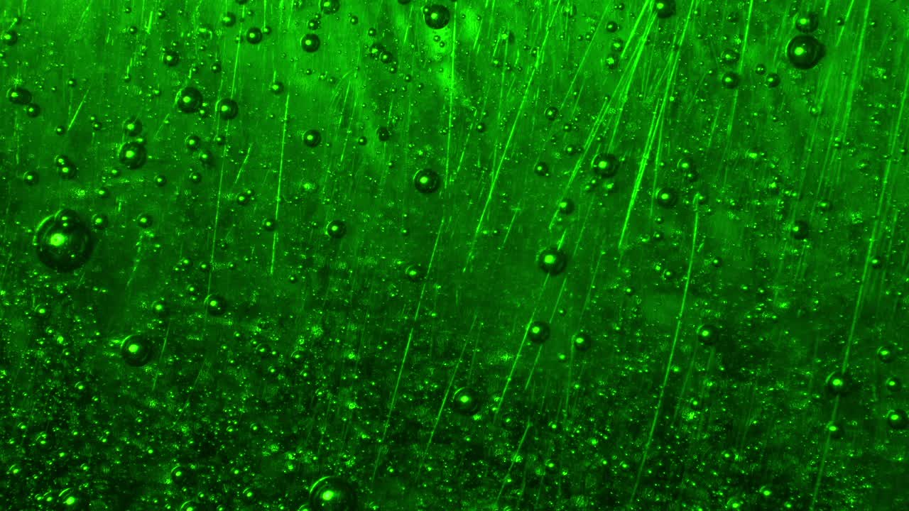Extreme close-up of green soap bubbles slowly rising in an abstract, surreal flow