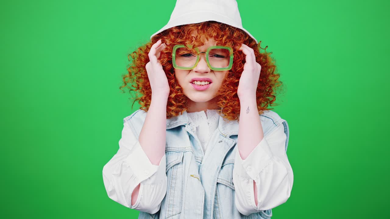 молодая рыжая кудрявая дама в очках и панамской шляпе вдыхает и массажирует свои болезненные храмы