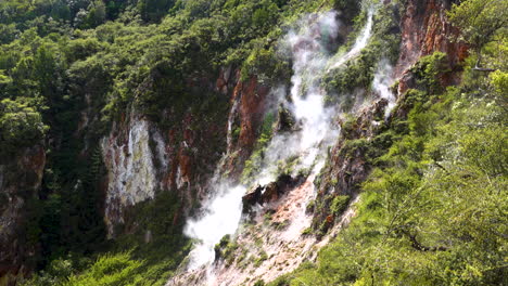 toxic sulfur steam rising up from geothermal springs along green mountains in nature