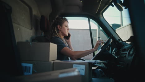 woman working in a delivery van, handling packages and communications