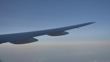 slick airplane wing flexing in flight, passenger view from window