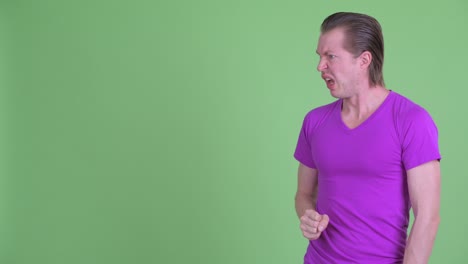 Studio shot of young man looking disgusted and frustrated while looking to copy space against green background