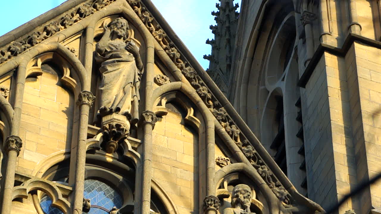 성당 의 외벽 과 정면 의 근접 촬영, 동상 과 성인 들 을 보여 주는 사진