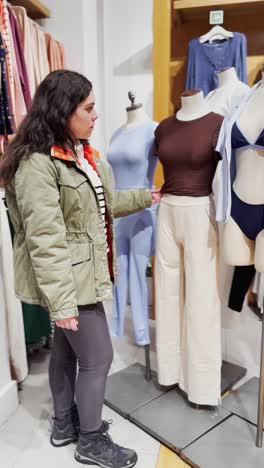 clothing store employee arranging clothes on mannequins