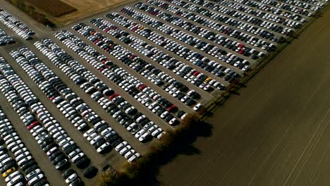 aerial footage of finished cars ready to be shipped on huge distribution center