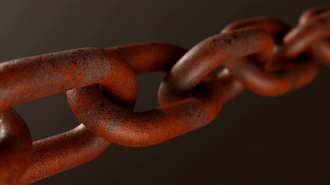 Primer plano de una cadena de metal oxidada que se extiende diagonalmente sobre un fondo oscuro y borroso, iluminada con una luz cálida y suave y poca profundidad de campo