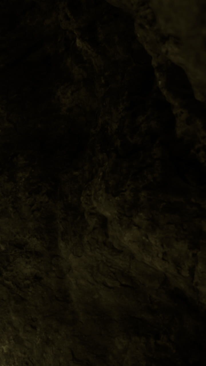 Esplorando la grotta buia e le sue texture rocciose sotto una luce fioca