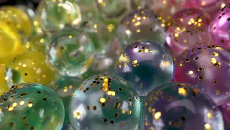 macro view of glass spheres wet abstract light reflections with colors and golden glitter, interesting 4k bright fun background footage