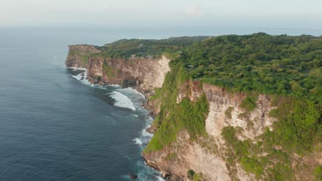 Luftdrohnenansicht-Der-Hohen-Klippen-Am-Meer,-Die-Mit-Grünem-Wald-Bedeckt-Sind