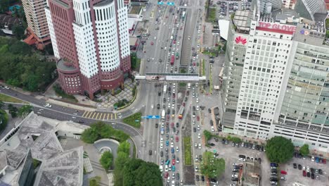 Aus-Der-Vogelperspektive-Nach-Oben-Geneigter-Schuss,-Der-Den-Dichten-Verkehr-Auf-Dem-Geschäftigen-Jln-Tun-Razak-Einfängt,-Umgeben-Von-Hochhäusern-Und-Wolkenkratzern-In-Der-Innenstadt-Von-Kuala-Lumpur,-Malaysia