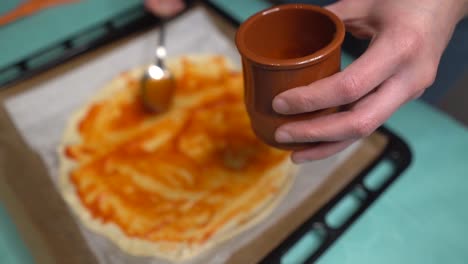 enfoque selectivo mujer poniendo salsa de tomate de un frasco en masa de pizza