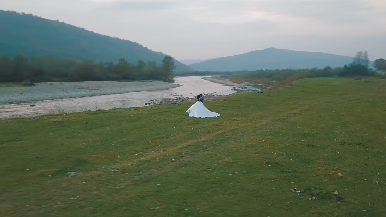 산 강 근처에서 달리는 결혼 부부. 신랑과 신부. 아리얼 뷰