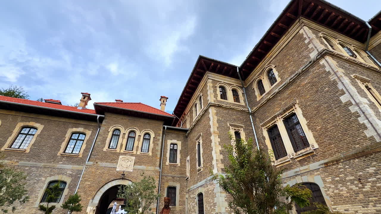 Admiring grey brick-wall façade of the famous landmark of Romania. The Cantacuzino Castle, Bu?teni from low angle view