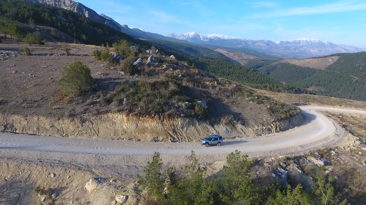 Vista aerea di un SUV che percorre una strada di montagna tortuosa