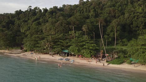 Tropeninsel-Drohne,-Trucking,-Rotierende-Aufnahme-Mit-Regenwald-Und-Palmen-Mit-Weißem-Sandstrand,-Kajaks,-Kleine-Strandbars-Mit-Einigen-Thailändischen-Inlandstouristen,-Die-Ein-Langes-Wochenende-Genießen