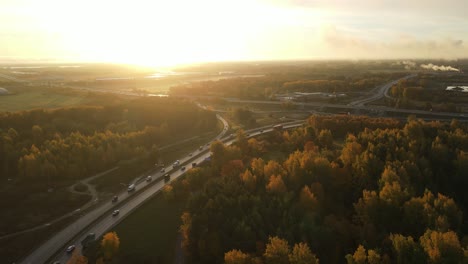 drone filming road with traffic near fall forest 4k