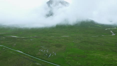 스코틀랜드 시골의 흰 구름에 숨겨진 buachaille etive mor 산봉우리를 드러내는 드론 샷