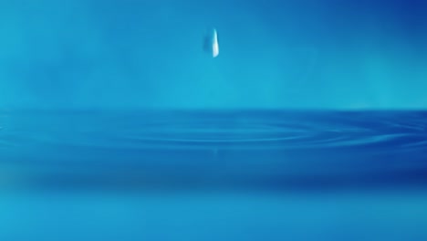 slow motion 4k video of a water surface with falling drops on a blue background. splashing water. studio shooting.