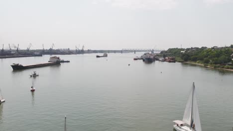 river scene with sailboats and cargo ships