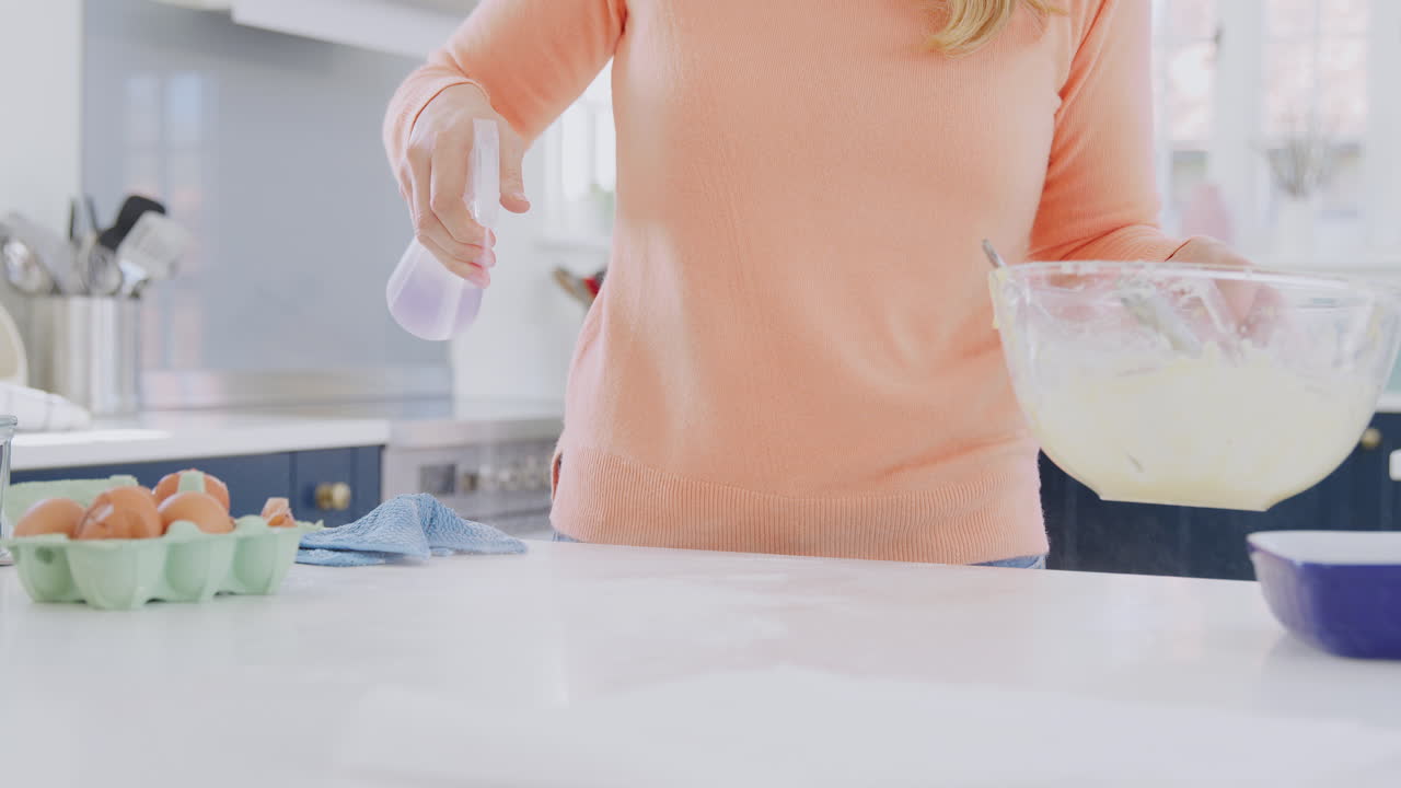 케이크 를 구운 후 스프레이 와 옷 으로 주방 카운터 를 청소 하는 여자