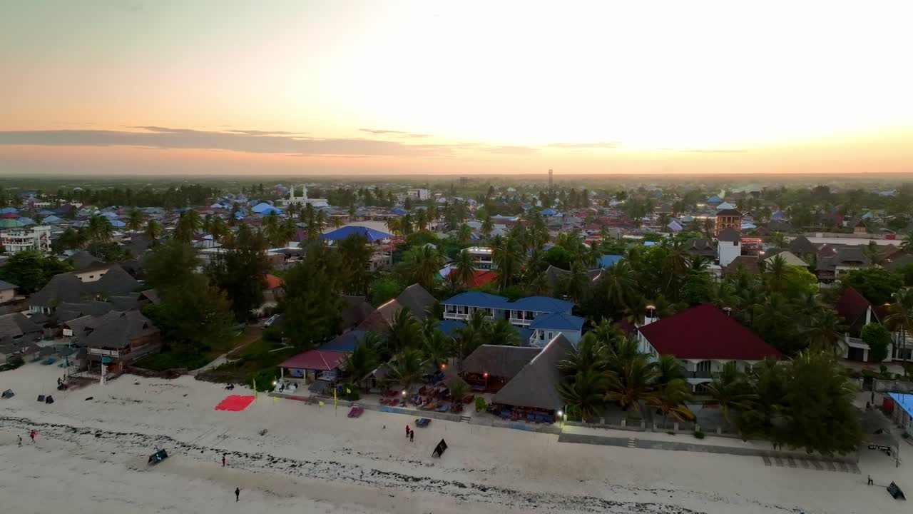 Drone'un alacakaranlıkta Paje'nin şehir camisine doğru uçuşunu izleyin; güneş, gökyüzünü sarı ve kırmızı tonlarda alev alev yakıyor