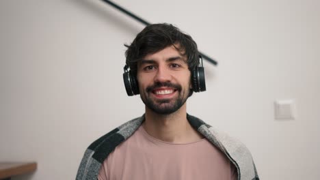 hombre barbudo sonriente con auriculares mirando a la cámara